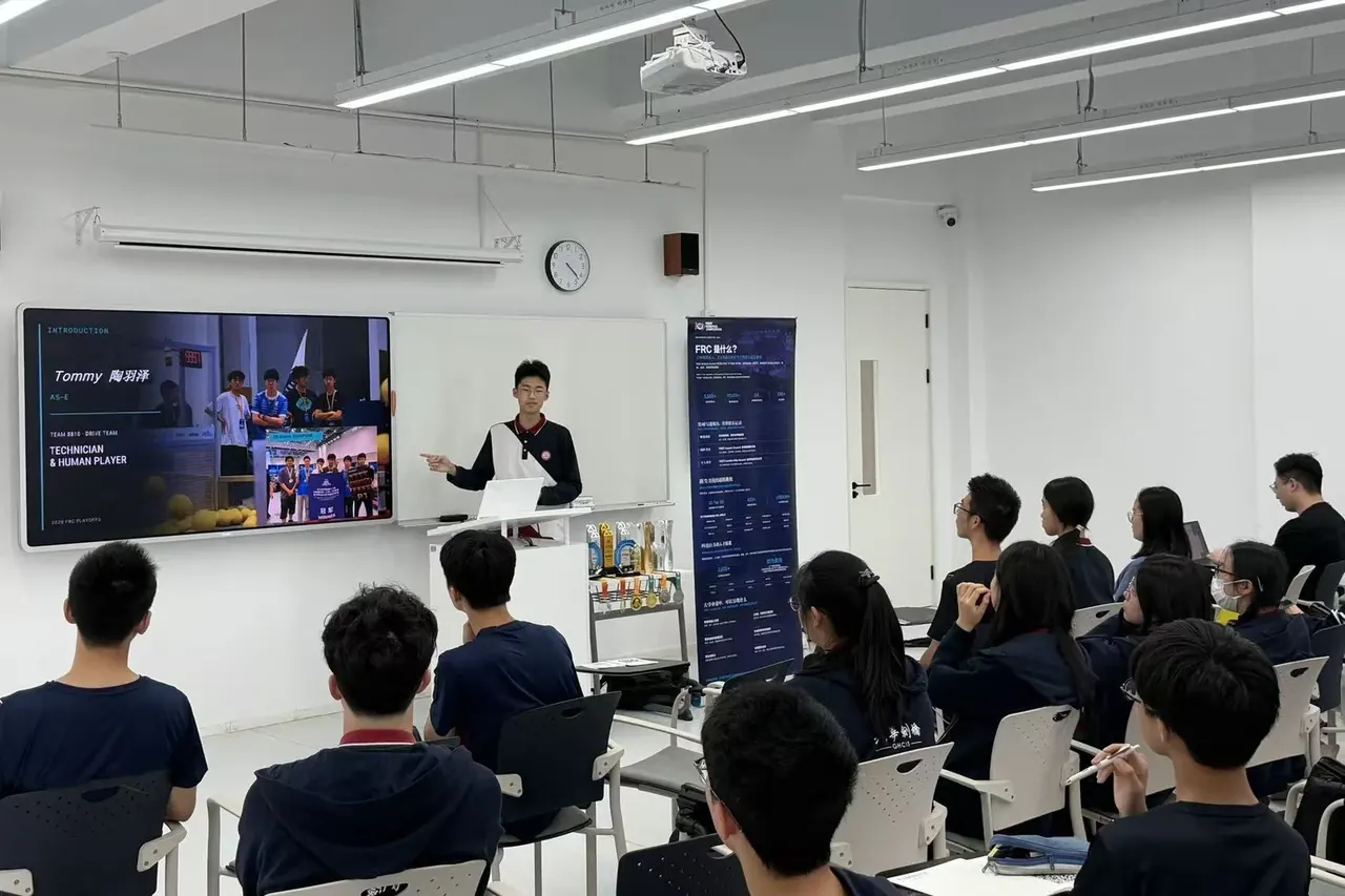 讲师在教室里向围坐的学生与来宾介绍机器人项目