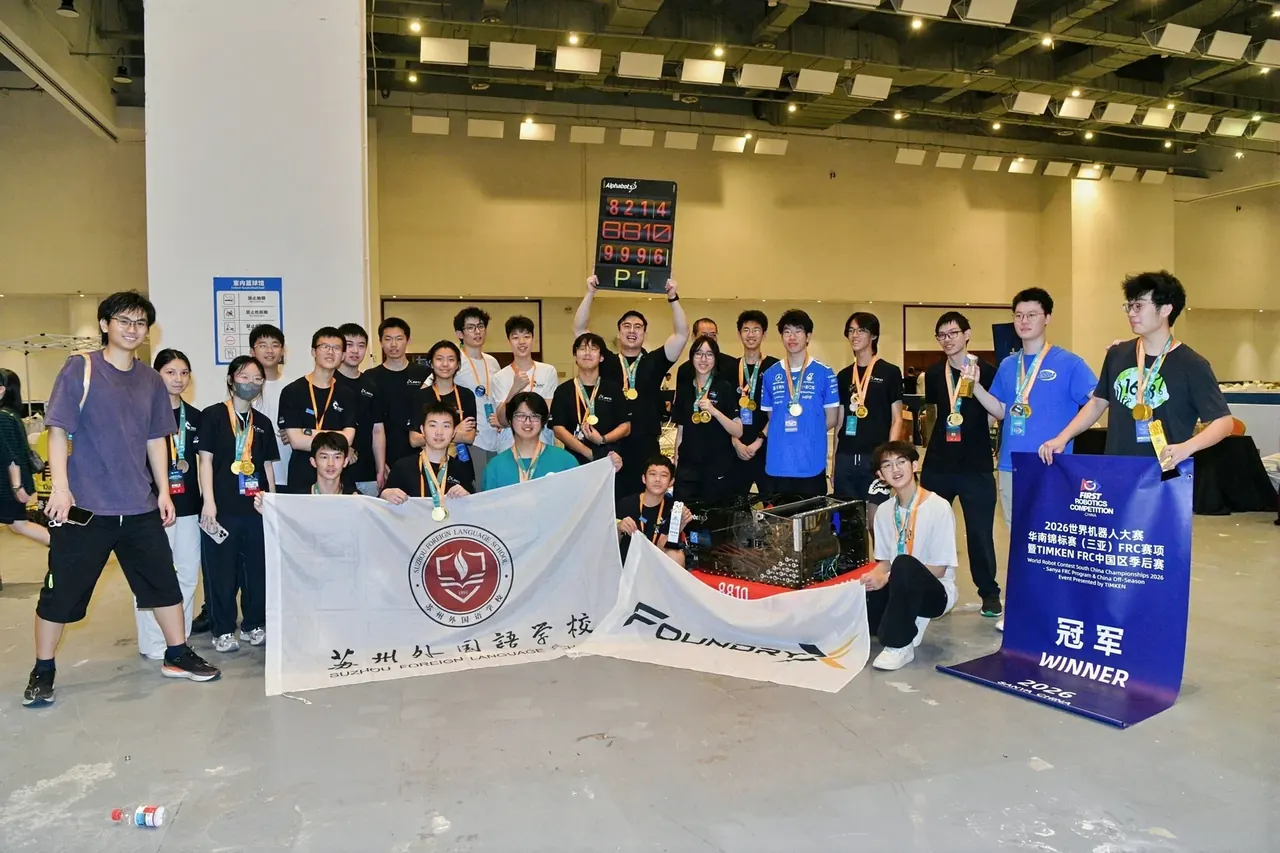 队员在赛场与机器人、队旗和冠军展板合影